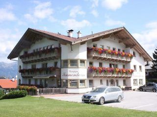 Traditional Alpine hotel in Innsbruck with decorative flower balconies, nestled against a backdrop of mountains